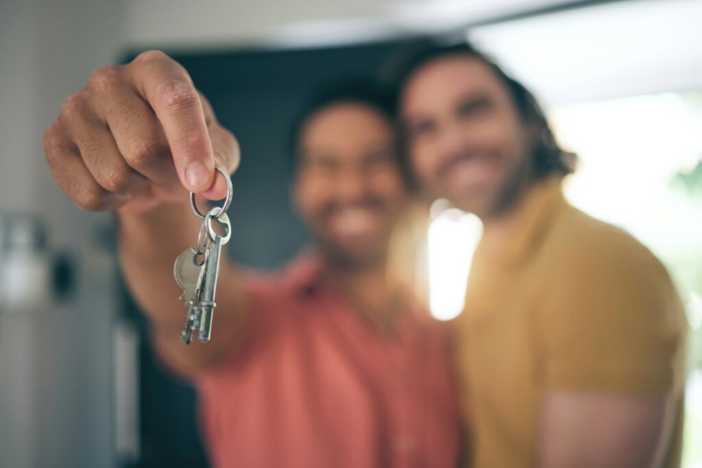Hand holding, keys and gay couple smile for real estate, success or new home celebration. Property,